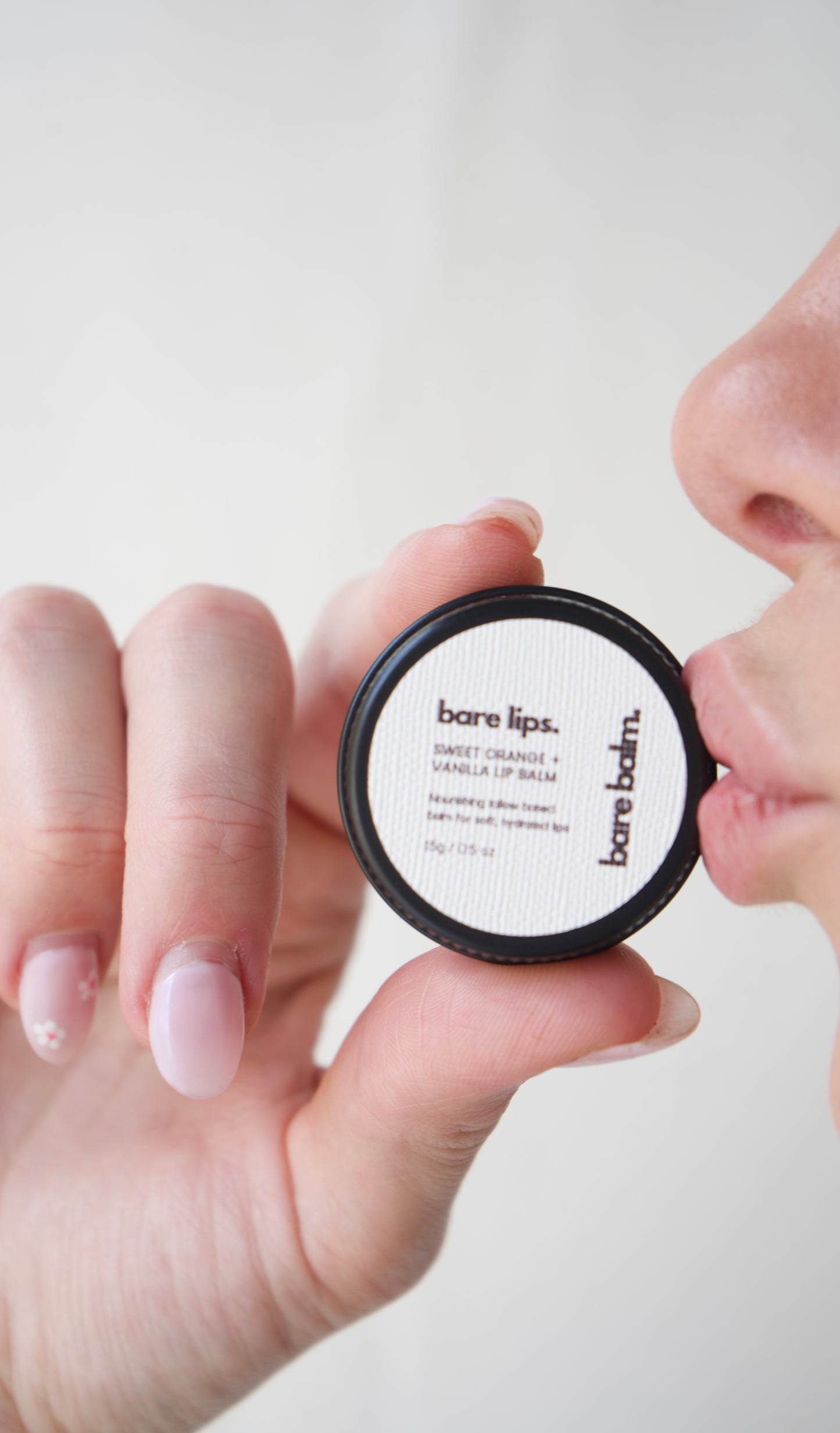 Person holding a BareMinerals lip balm against a white background